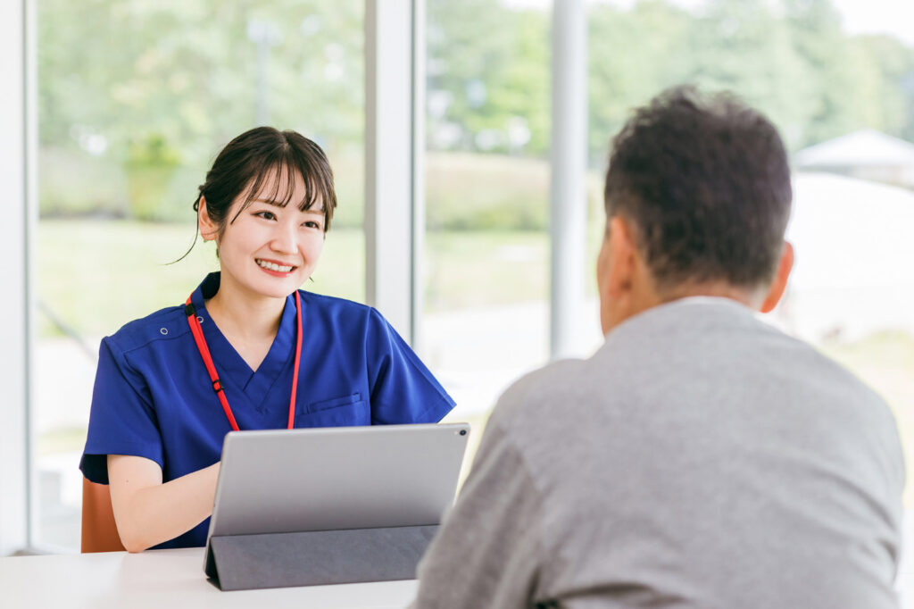 訪問看護スタッフが利用者と向き合い笑顔で相談を受ける様子